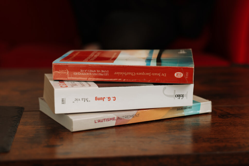 Livres posés sur une surface sombre, évoquant la réflexion et la connaissance. Carl Gustav JUNG. Dr Jean-Jacques CHARBONIER, les preuves scientifiques d'une vie après la vie. Julie DACHEZ, l'autisme autrement.